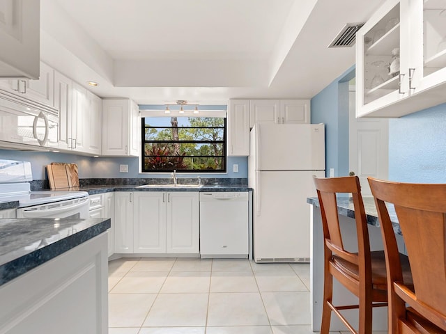 kitchen with white appliances, a sink, white cabinetry, and light tile patterned flooring