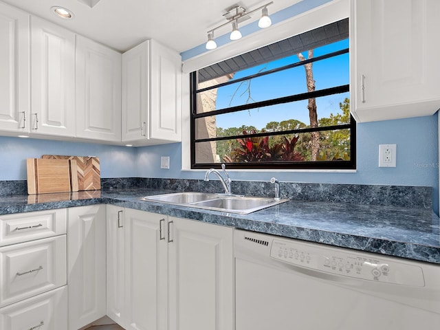 kitchen featuring white dishwasher, a sink, white cabinetry, dark countertops, and recessed lighting