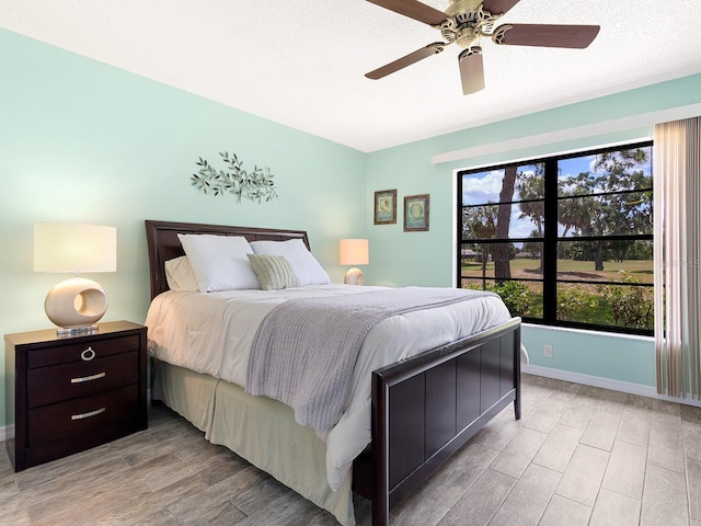 bedroom with light wood-style floors, baseboards, and a ceiling fan