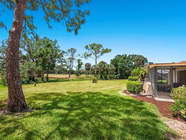view of grassy yard featuring a sunroom