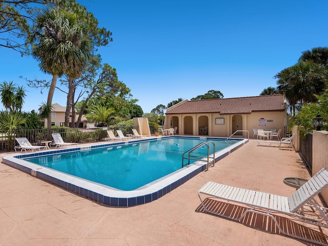 community pool with fence and a patio