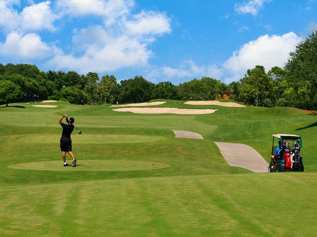 view of community featuring view of scattered trees, golf course view, and a lawn