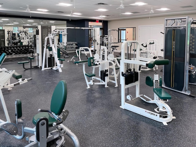 exercise room with ceiling fan and a drop ceiling