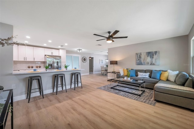 living area featuring light wood-style flooring, ceiling fan, recessed lighting, and baseboards