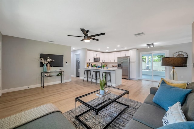living area with light wood finished floors, ceiling fan, baseboards, and recessed lighting