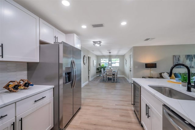 kitchen with stainless steel appliances, a sink, beverage cooler, white cabinetry, and recessed lighting