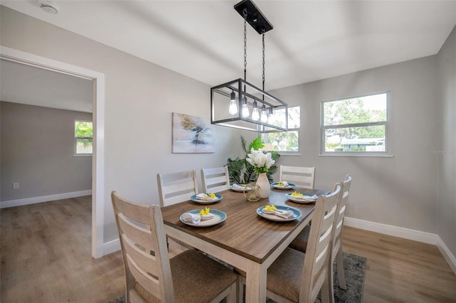 dining area featuring baseboards, light wood-style flooring, and a chandelier