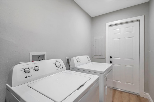 washroom featuring washing machine and clothes dryer, light wood-type flooring, and electric panel
