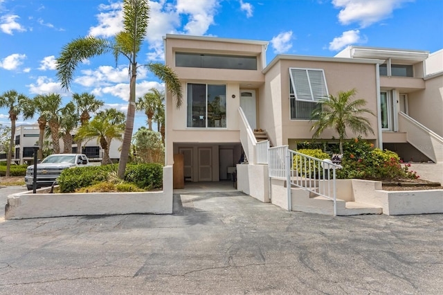 townhome / multi-family property with stairway, stucco siding, and a carport