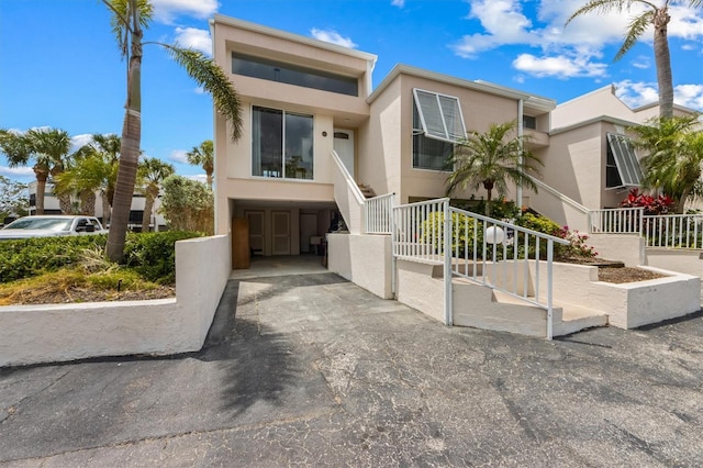 view of front of house with stairs, stucco siding, and a carport