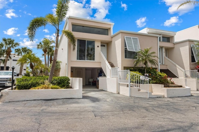 multi unit property featuring stairs, a carport, and stucco siding