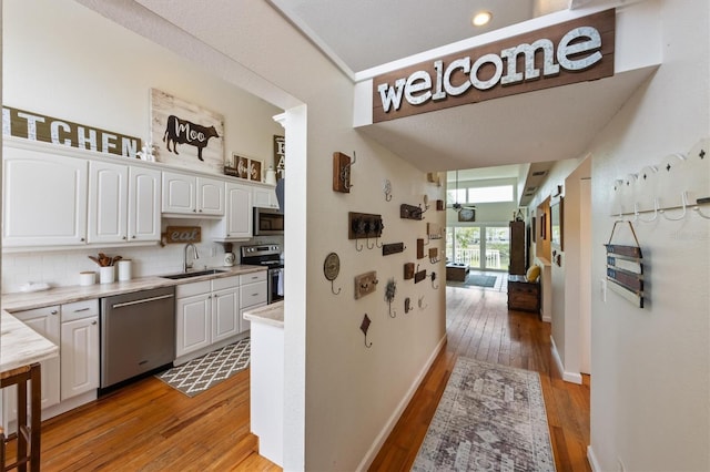 corridor featuring a sink, light wood-style floors, and baseboards