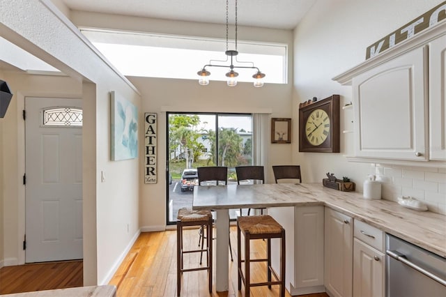 kitchen with dishwasher, light wood-style floors, a peninsula, and plenty of natural light