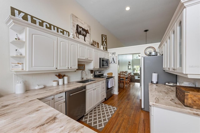 kitchen featuring stainless steel appliances, a sink, white cabinetry, vaulted ceiling, and tasteful backsplash