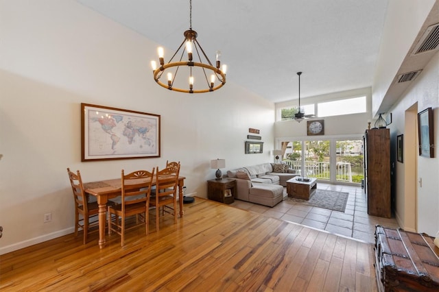 dining space featuring high vaulted ceiling, wood-type flooring, a chandelier, and a ceiling fan