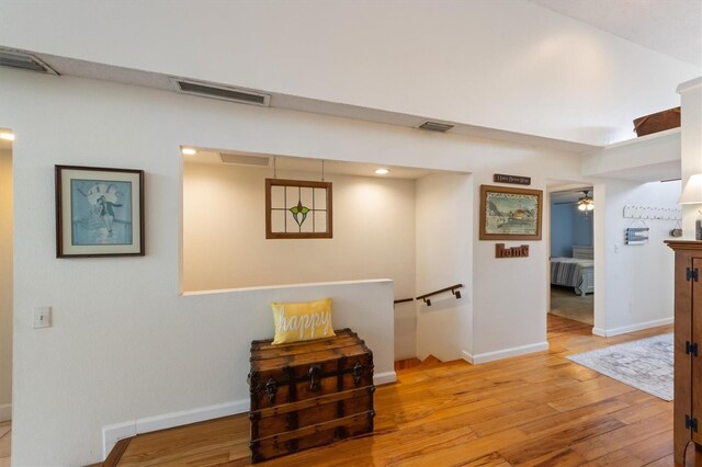 corridor with light wood-style flooring, baseboards, and an upstairs landing