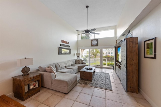 living room with ceiling fan, light tile patterned floors, baseboards, and a high ceiling