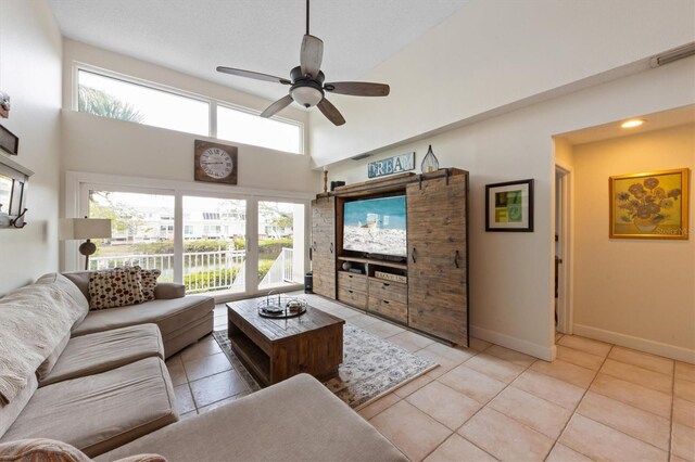 living area featuring a ceiling fan, tile patterned floors, a high ceiling, and baseboards