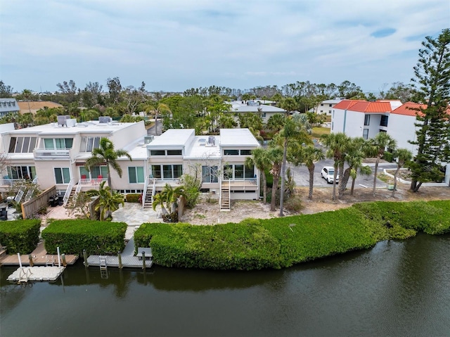 back of property with stairway, a water view, and a residential view