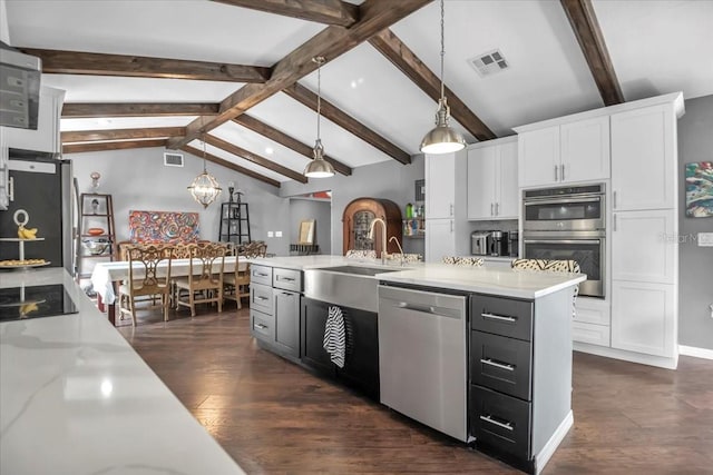 kitchen featuring appliances with stainless steel finishes, a sink, white cabinets, dark wood-style flooring, and decorative light fixtures