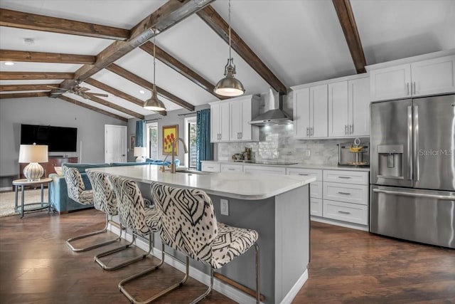 kitchen with stainless steel fridge with ice dispenser, wall chimney exhaust hood, a sink, and a breakfast bar area
