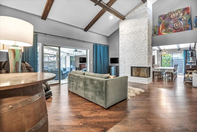 living room featuring beam ceiling, plenty of natural light, hardwood / wood-style flooring, high vaulted ceiling, and a fireplace