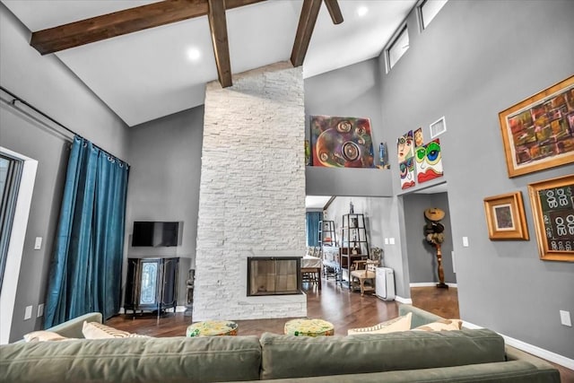 living room with high vaulted ceiling, wood finished floors, a stone fireplace, beamed ceiling, and baseboards