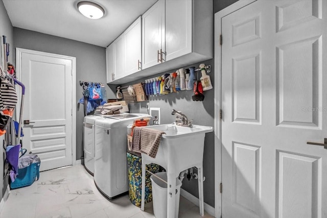 washroom featuring cabinet space, washing machine and dryer, light marble finish floors, and baseboards