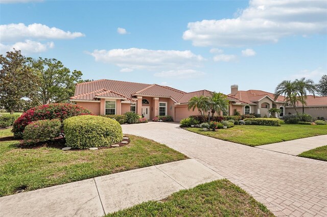 431 Fieldstone Dr, Venice, FL 34292 - mediterranean / spanish house with decorative driveway, a garage, a tile roof, stucco siding, and a front yard