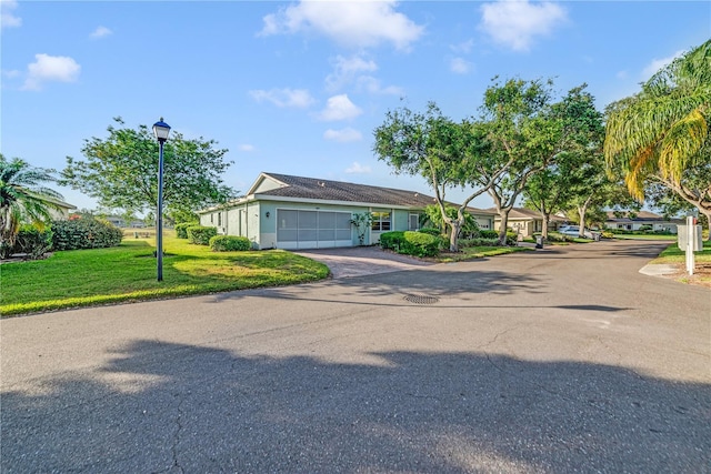 2607 Lancaster Dr Unit 35, Sun City Center, FL 33573 - view of front of property featuring asphalt driveway, an attached garage, a front lawn, and stucco siding