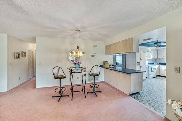 2607 Lancaster Dr Unit 35, Sun City Center, FL 33573 - kitchen featuring a peninsula, light carpet, white electric range oven, a textured ceiling, and a chandelier