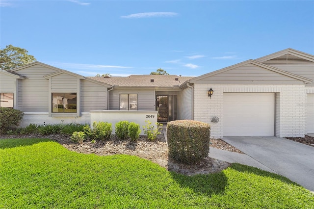 view of front of property with brick siding, an attached garage, concrete driveway, and a front lawn