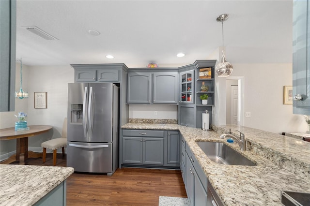 kitchen with stainless steel fridge, a sink, gray cabinets, light stone counters, and recessed lighting