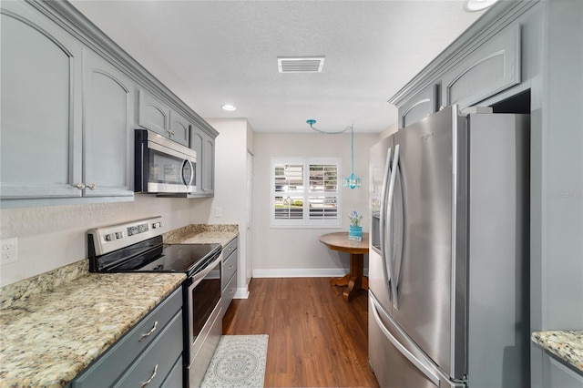 kitchen featuring appliances with stainless steel finishes, gray cabinetry, baseboards, dark wood-style floors, and light stone counters