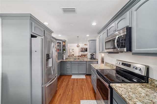 kitchen with appliances with stainless steel finishes, gray cabinetry, light wood-style floors, light stone countertops, and recessed lighting