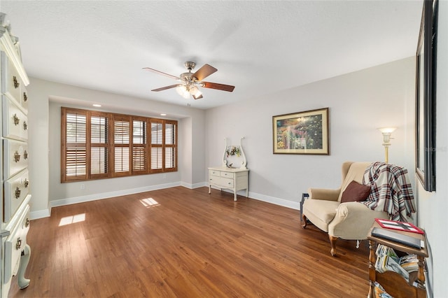 living area with a ceiling fan, baseboards, and wood finished floors