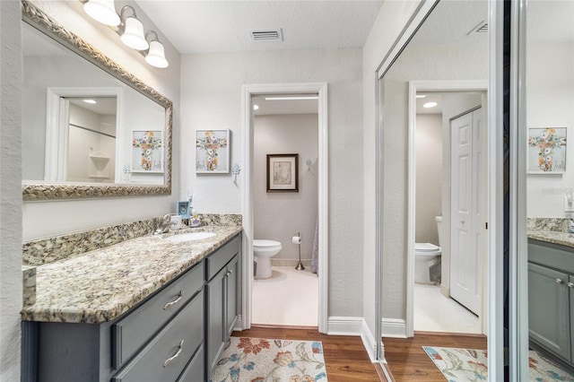 bathroom featuring toilet, wood finished floors, vanity, and baseboards