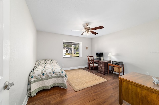 bedroom with dark wood-style floors, a desk, baseboards, and ceiling fan