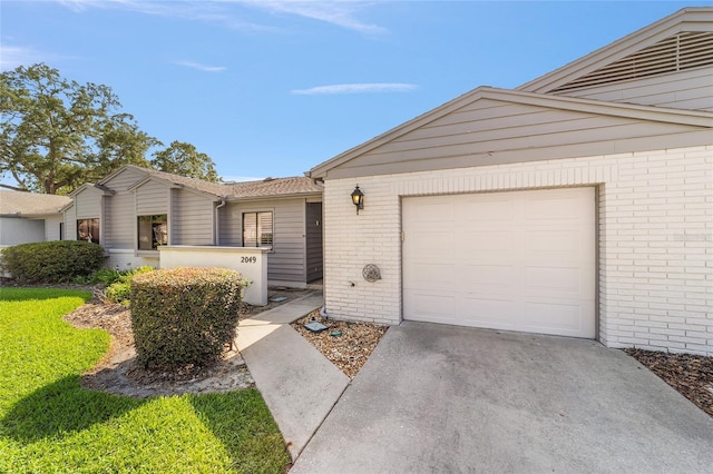 view of front of property with brick siding, an attached garage, and driveway
