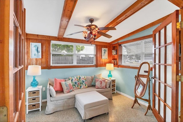 living area featuring ceiling fan, baseboards, carpet flooring, and wood walls