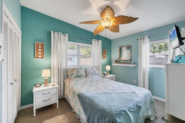 carpeted bedroom featuring vaulted ceiling, multiple windows, baseboards, ceiling fan, and a closet