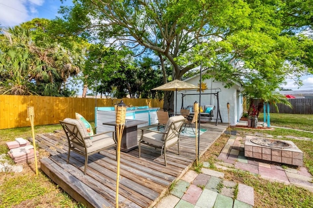 wooden terrace with an outdoor fire pit, a fenced backyard, and an outdoor structure