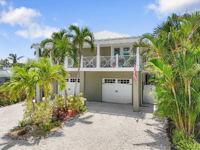 229 S Harbor Dr, Holmes Beach, FL 34217 - coastal inspired home featuring stucco siding, gravel driveway, a standing seam roof, a garage, and metal roof