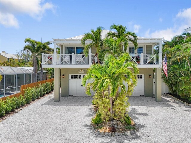 229 S Harbor Dr, Holmes Beach, FL 34217 - beach home with gravel driveway, an attached garage, and a balcony