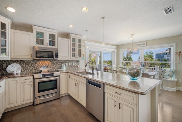 229 S Harbor Dr, Holmes Beach, FL 34217 - kitchen featuring appliances with stainless steel finishes, a sink, a peninsula, dark wood-style flooring, and a textured ceiling