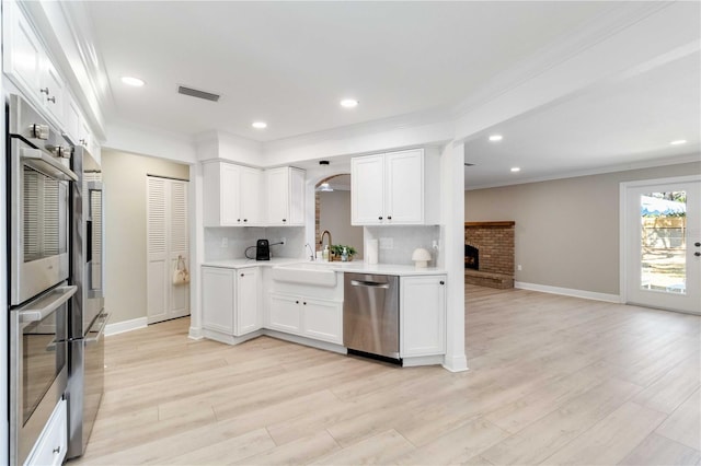 kitchen with appliances with stainless steel finishes, a sink, ornamental molding, baseboards, and tasteful backsplash