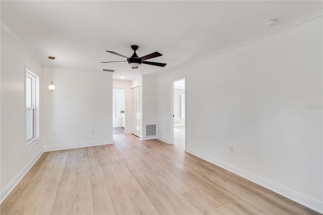 empty room featuring light wood finished floors, ornamental molding, a ceiling fan, baseboards, and plenty of natural light