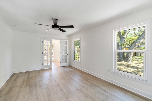 spare room with french doors, ornamental molding, light wood-style floors, baseboards, and ceiling fan