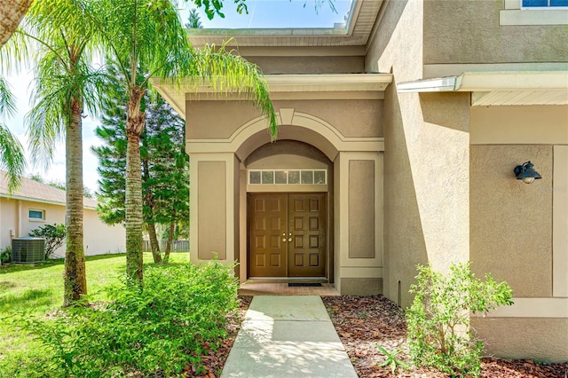entrance to property featuring stucco siding and central AC unit