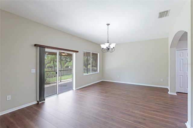 unfurnished room featuring dark wood-style floors, baseboards, arched walkways, and a chandelier